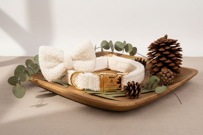 White fluffy dog collar with gold buckle on a wooden stand, pine cone on beige background